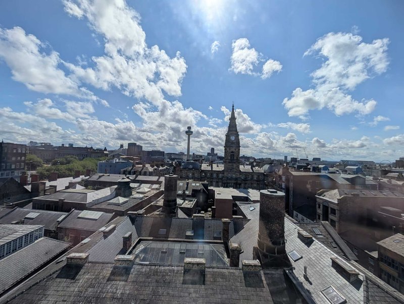 Urban rooftop view with historic church spire and city skyline under blue sky