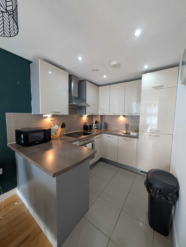 Modern kitchen with white cabinetry, dark countertop island, stainless steel appliances and tile flooring