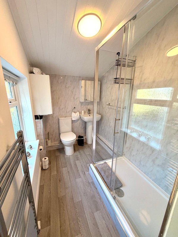 Modern bathroom with shower enclosure, toilet, sink and wooden flooring