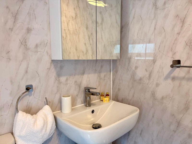Modern bathroom with marble-effect tiles, wall-mounted sink, mirror cabinet and towel rail