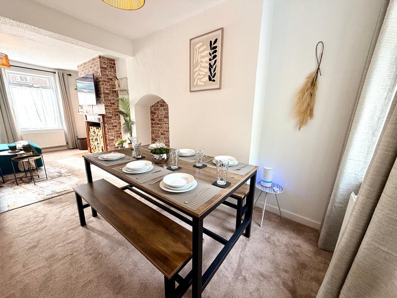 Dining room with wooden table, place settings, decorative wall art and pampas grass