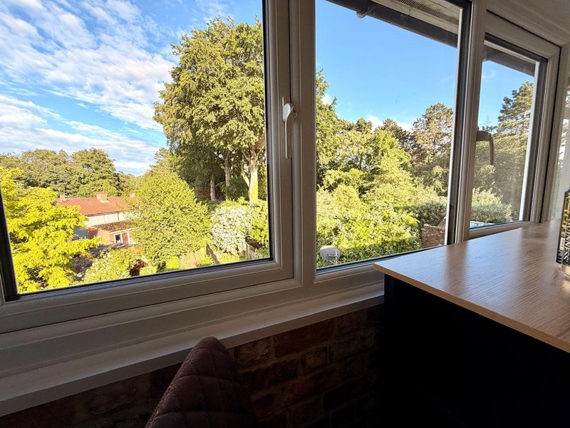 Modern workspace with desk overlooking garden views through large windows