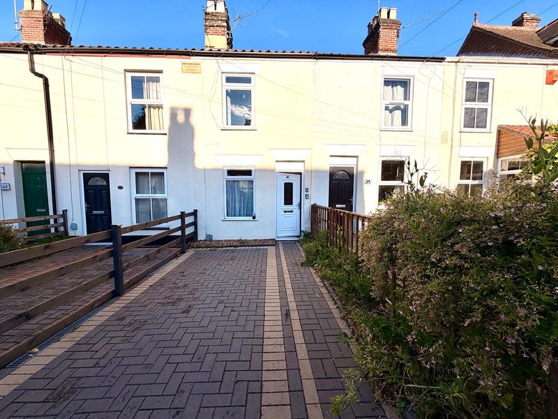 Terraced houses with cream-colored facades, paved courtyard, and green hedging