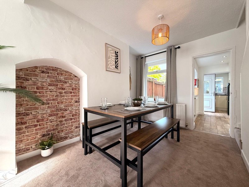 Bright dining area with black table and benches, exposed brick wall, pendant light fixture