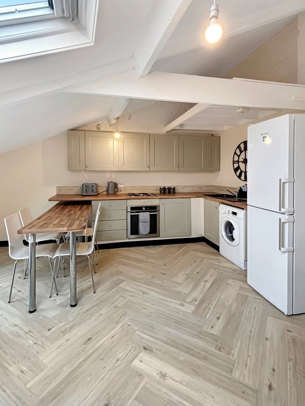 Modern kitchen with cream cabinets, white appliances, dining table and herringbone flooring