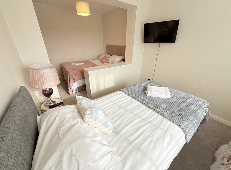 Modern bedroom with twin beds, bedside lamp, wall-mounted TV and neutral decor
