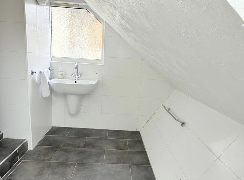 Bathroom with wall-mounted sink, window, white tiles and grey floor tiles