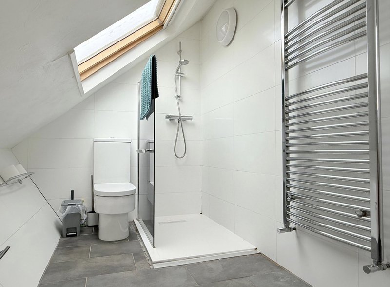 Modern bathroom with shower enclosure, toilet, heated towel rail and skylight
