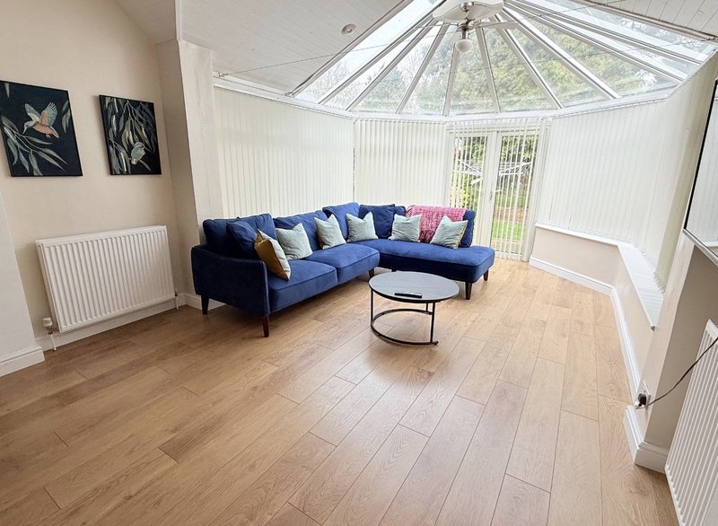 Bright living room with blue corner sofa, round coffee table, wooden flooring and skylight