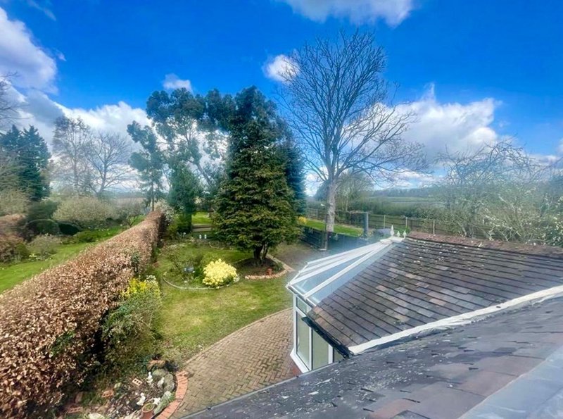 Aerial view of property garden with landscaping, trees, and modern roofing