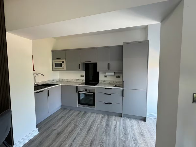 Modern kitchen with grey cabinetry, integrated appliances, grey wood-effect flooring