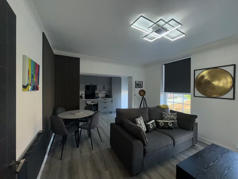 Modern living room with black sofa, dining table, geometric ceiling light and framed artwork