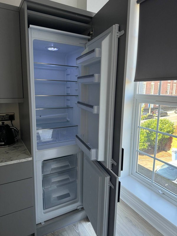 Open refrigerator-freezer in modern kitchen with window view of garden