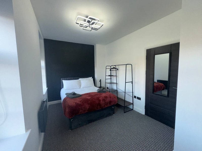 Modern bedroom with single bed, dark headboard, burgundy bedding and dark doors