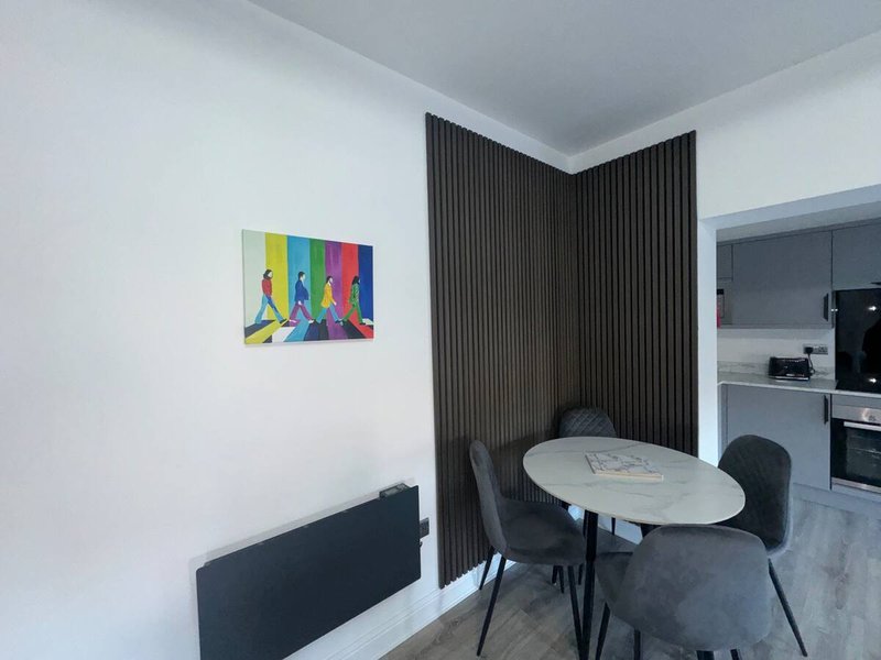 Modern dining area with round white table, black chairs, and colorful pop art wall decor