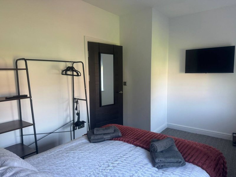 Bedroom with bunk bed, wall-mounted TV, door and red cushions on bed