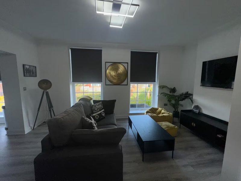 Modern living room with dark sofa, coffee table, TV, tripod lamp and plant decor