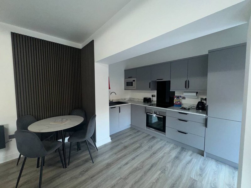 Modern kitchen with grey cabinetry, dining table and chairs, wooden flooring