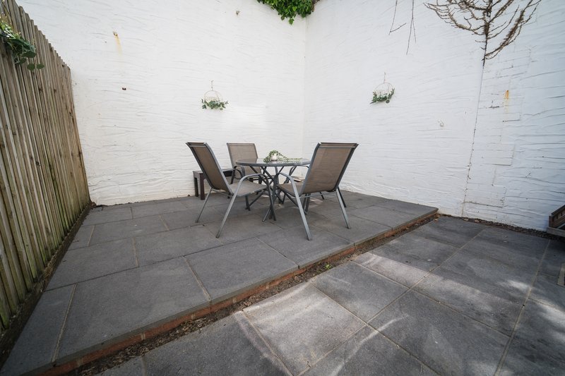Outdoor patio area with table, chairs, white brick walls and wooden fence