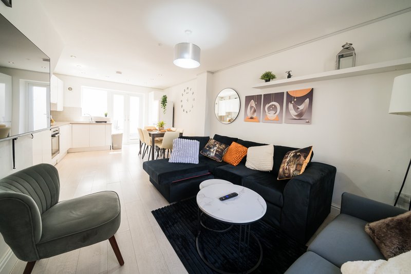 Open-plan living room with black sofa, armchairs, coffee table and dining area beyond