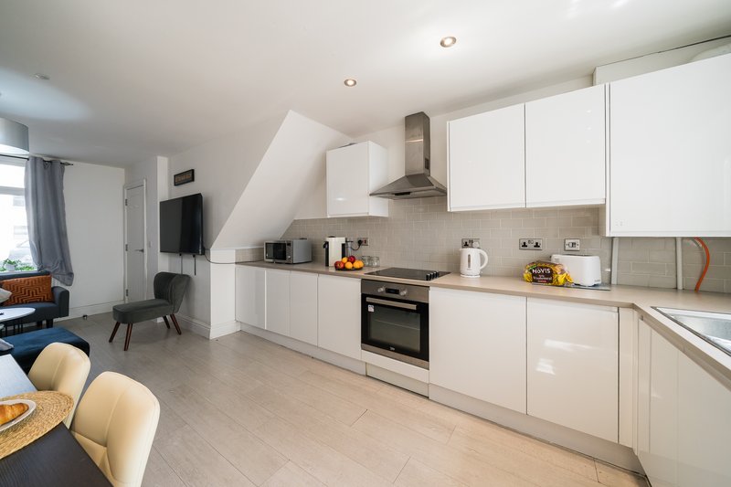 Open-plan kitchen and living area with white cabinetry, stainless steel appliances, dining table
