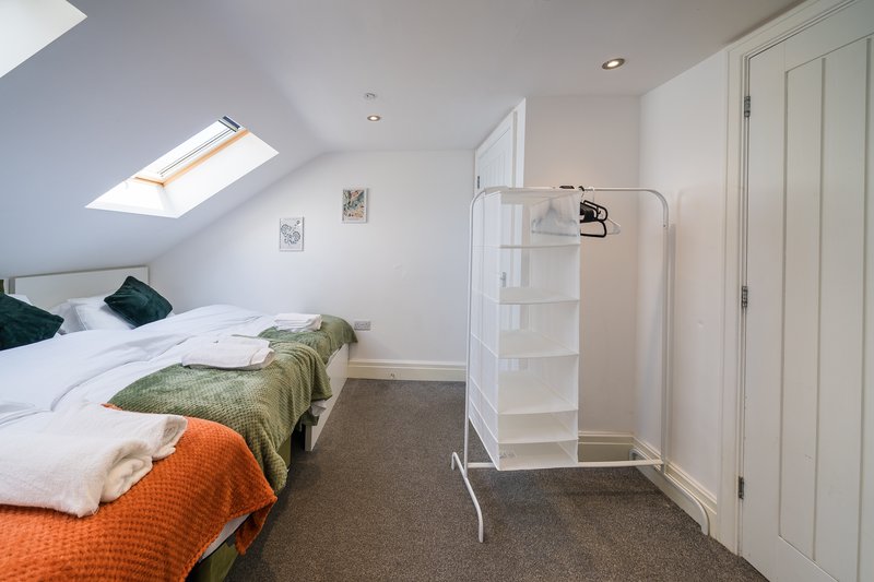 Attic bedroom with single bed, skylight, white shelving unit and fitted wardrobes