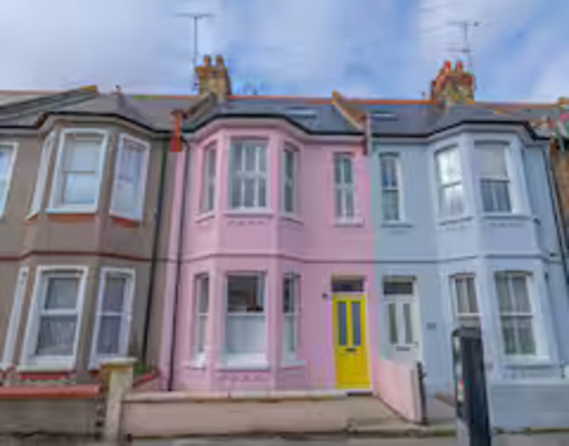 Row of colorful Victorian terraced houses with bay windows and yellow door