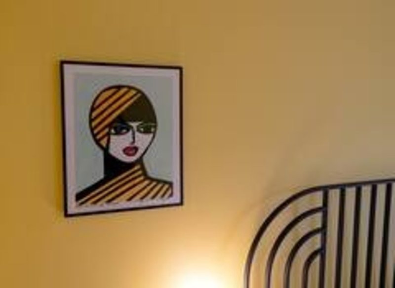 Yellow bedroom wall with framed pop-art portrait and curved wall feature