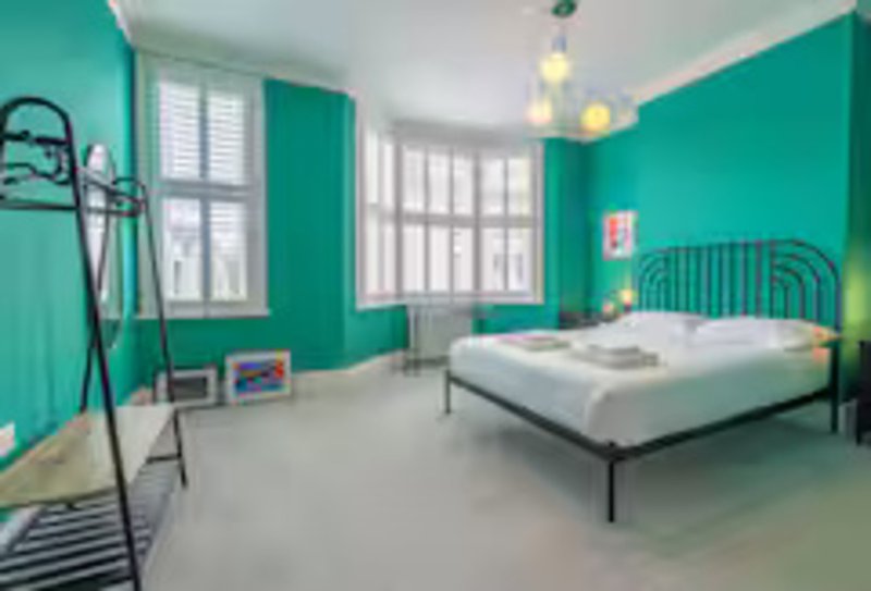 Bright turquoise bedroom with double bed, pendant lights, large windows and modern furnishings