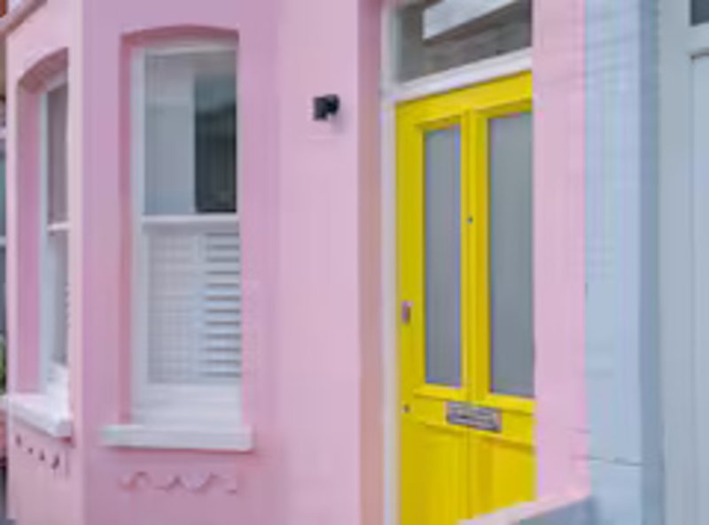 Pink building exterior with yellow door, white-framed window and light fixture