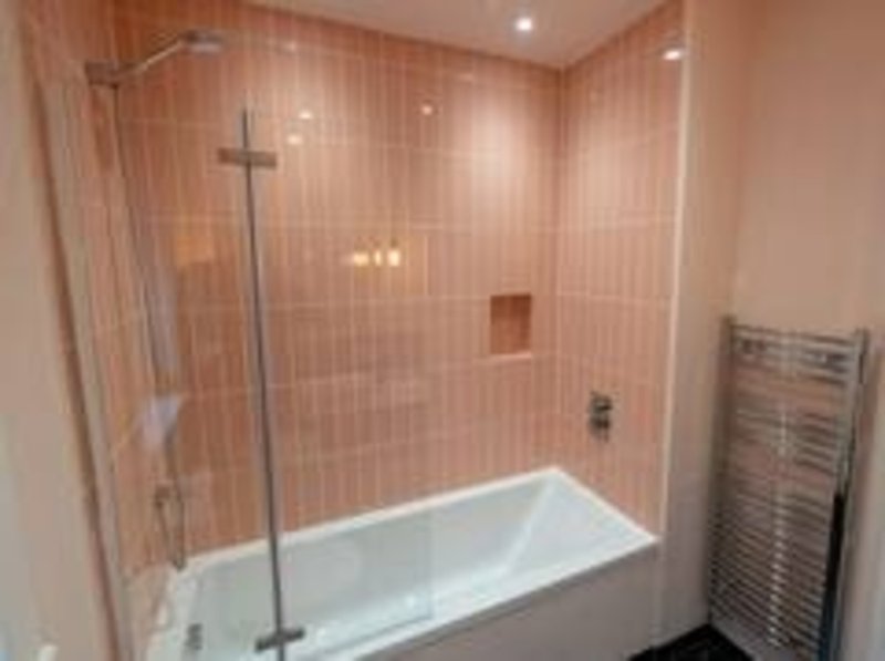 Modern bathroom with walk-in shower, pink tile walls, white bathtub and heated towel rail