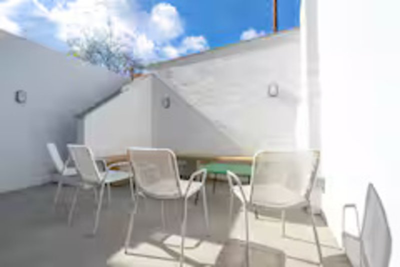 Modern rooftop terrace with white chairs, small table, and clear sky view