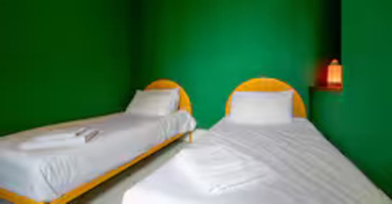 Bright green bedroom with two single beds, white bedding and yellow headboards