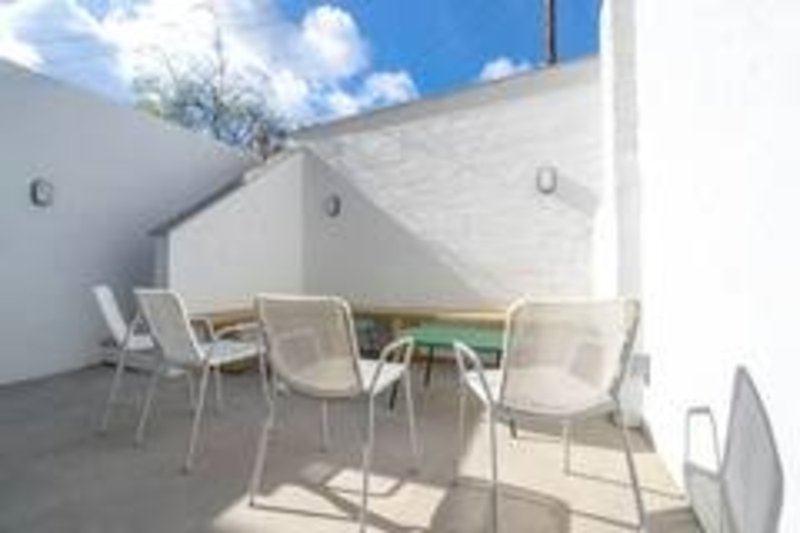 Outdoor terrace with modern seating, round table, white walls and blue sky