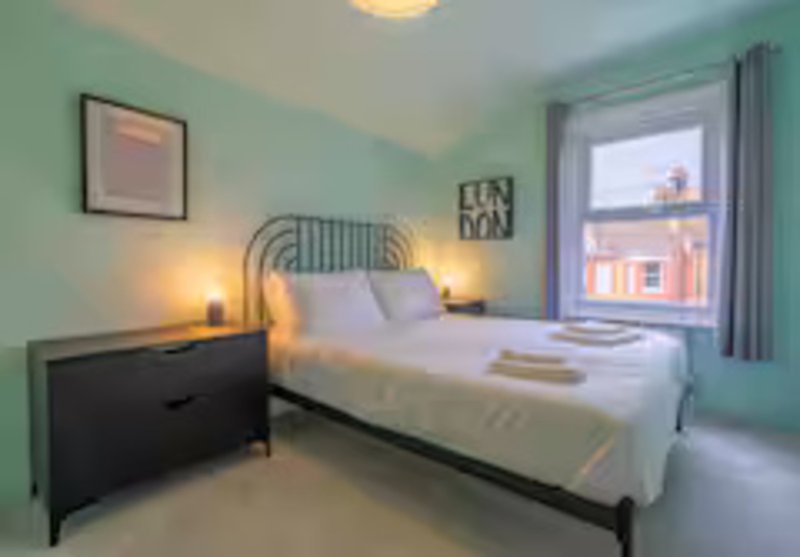 Modern bedroom with double bed, metal headboard, black nightstand, and mint green walls
