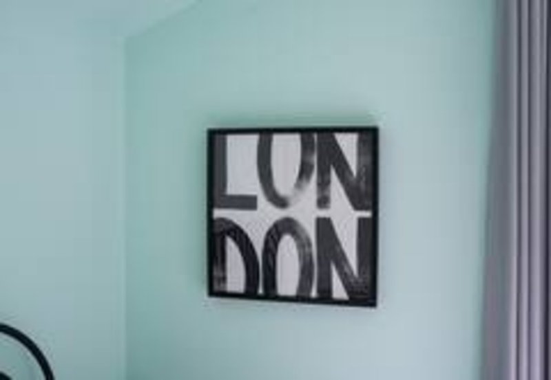 Light turquoise bedroom wall with black framed London wall art and curtain