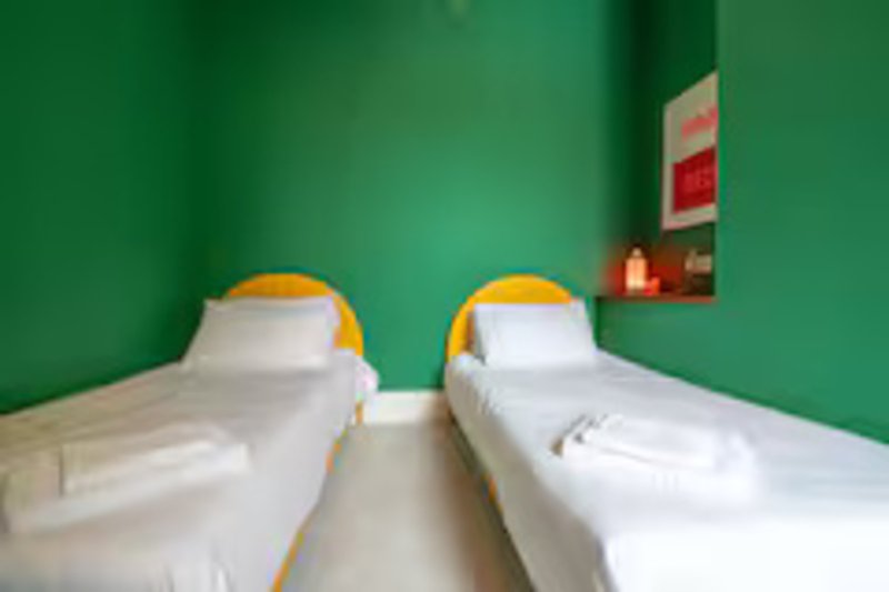 Twin bedroom with white beds, yellow headboards, and green wall