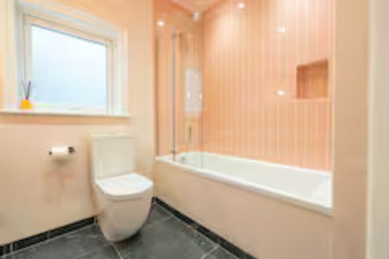 Modern bathroom with toilet, shower enclosure, window and peach-toned walls