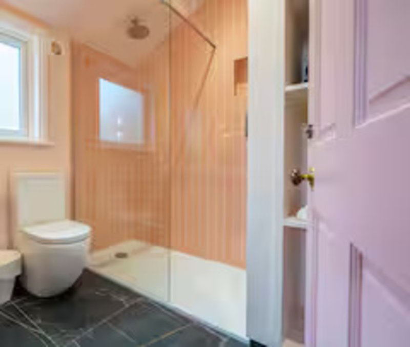 Modern bathroom with toilet, walk-in shower, wooden panelling and purple door