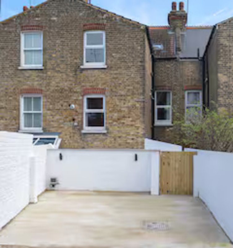 Brick terraced house with paved courtyard, white walls and wooden gate