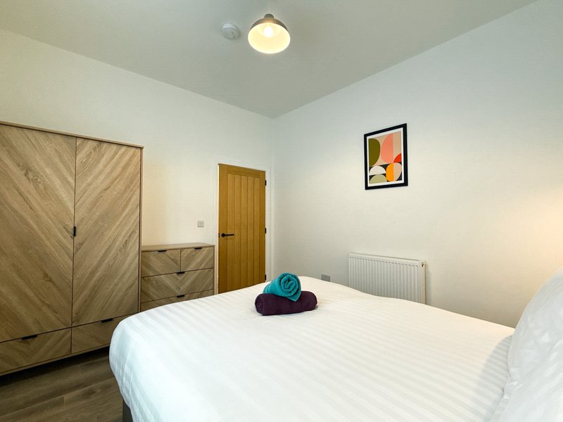 Bedroom with double bed, wooden wardrobe, framed wall art, and ceiling light