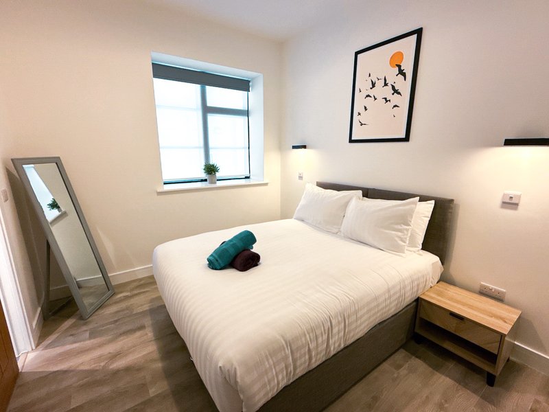 Modern bedroom with double bed, wooden nightstand, standing mirror and wall art