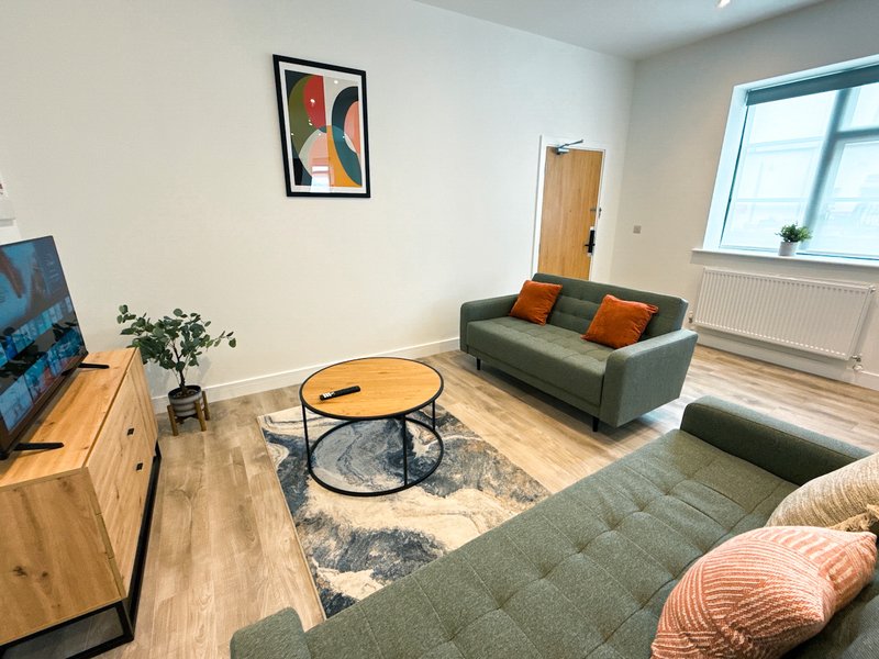 Modern living room with green sofa, wooden TV unit, round coffee table and large window