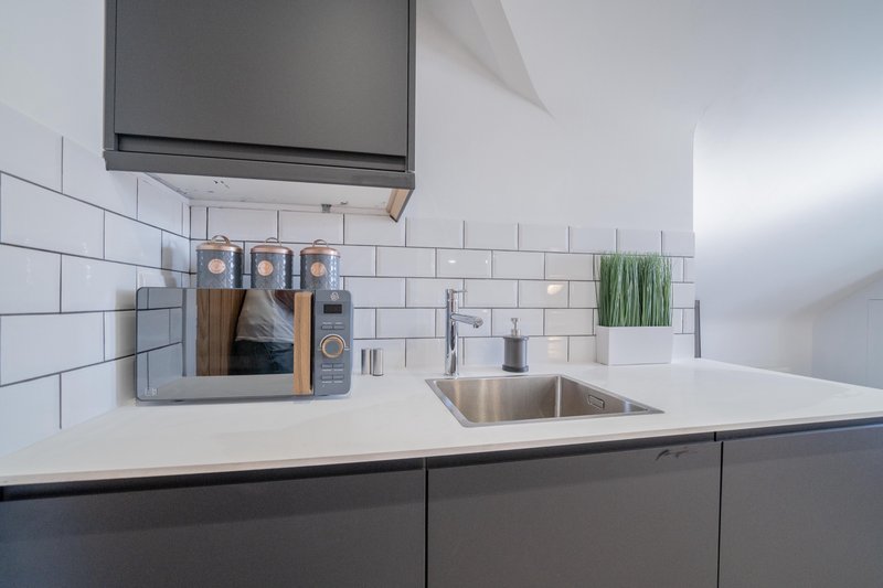 Modern kitchen with white subway tile backsplash, stainless steel sink, and dark cabinetry