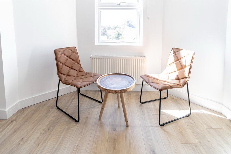 Bright minimalist room with two tan quilted chairs flanking small round table and window