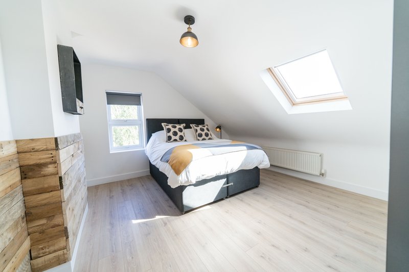 Bright attic bedroom with double bed, wooden flooring, skylight window and pendant light