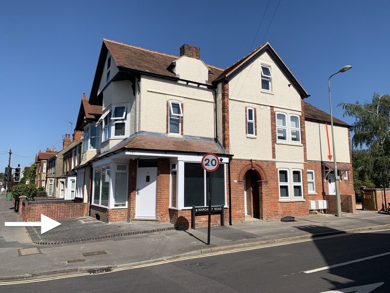 Multi-story brick and cream building with pitched roof, shop frontage and residential upper floors