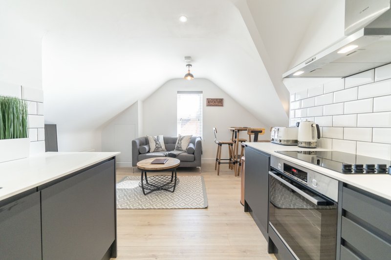 Open-plan kitchen and living area with dark cabinetry, stainless steel appliances, wooden flooring and seating area