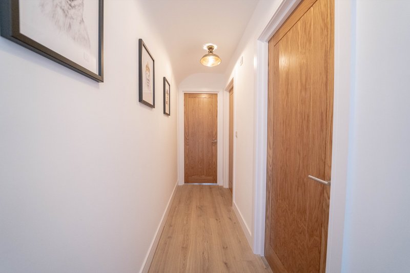Bright hallway with wooden doors, laminate flooring, white walls and framed artwork