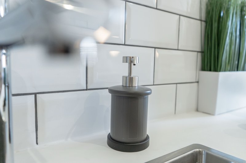 Modern bathroom with white subway tile backsplash, soap dispenser, and potted plant on counter